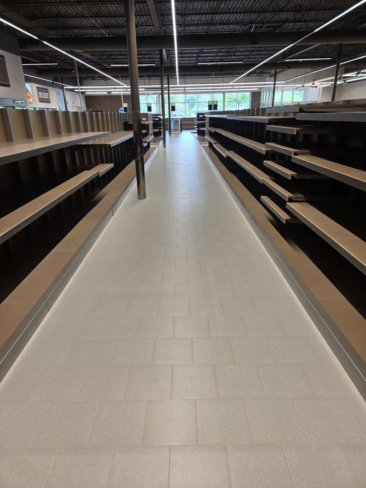 Empty grocery aisle after the final clean, shelving wiped down and tile floor clean to the far wall